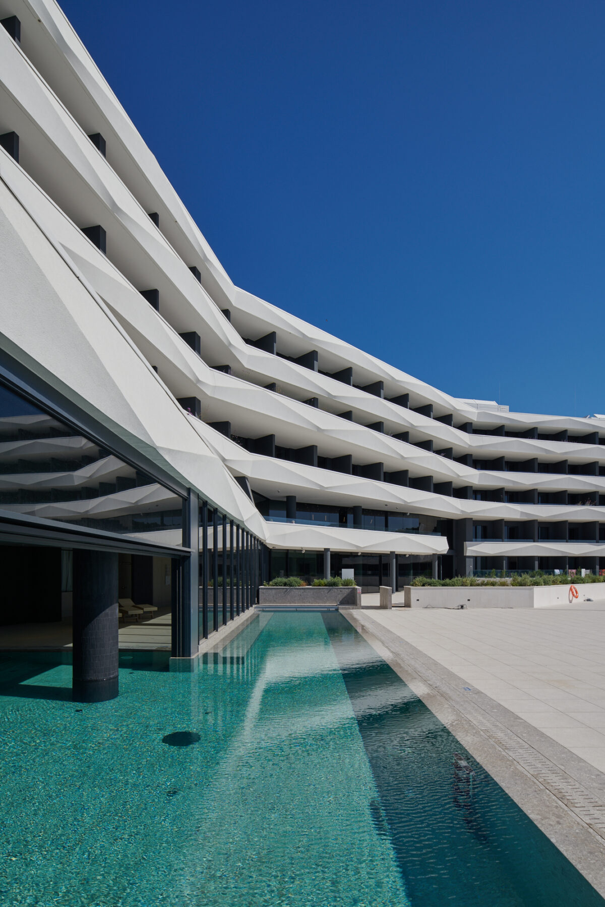 A large hotel with many windows and a pool.