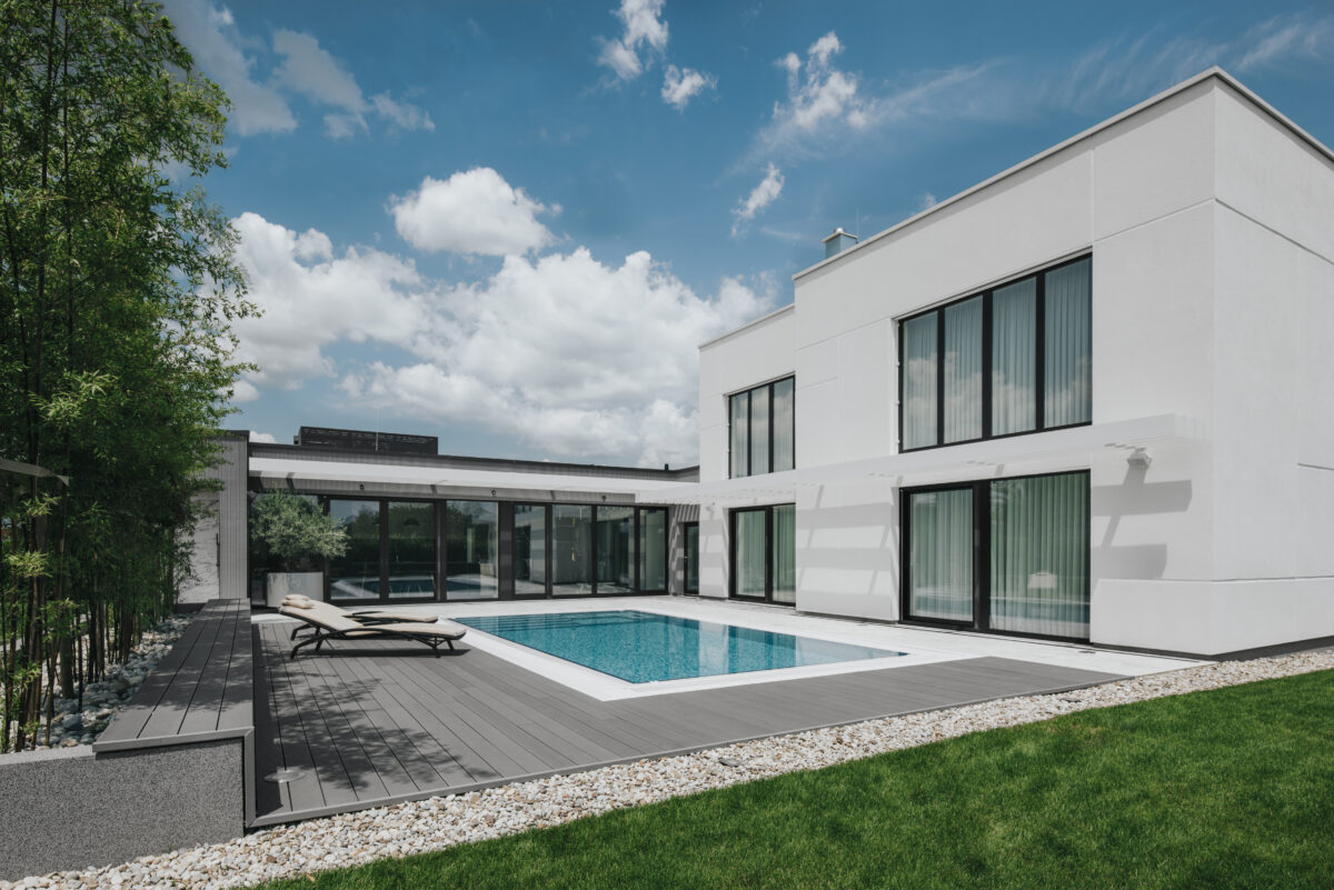 A large white building with large windows and a pool.