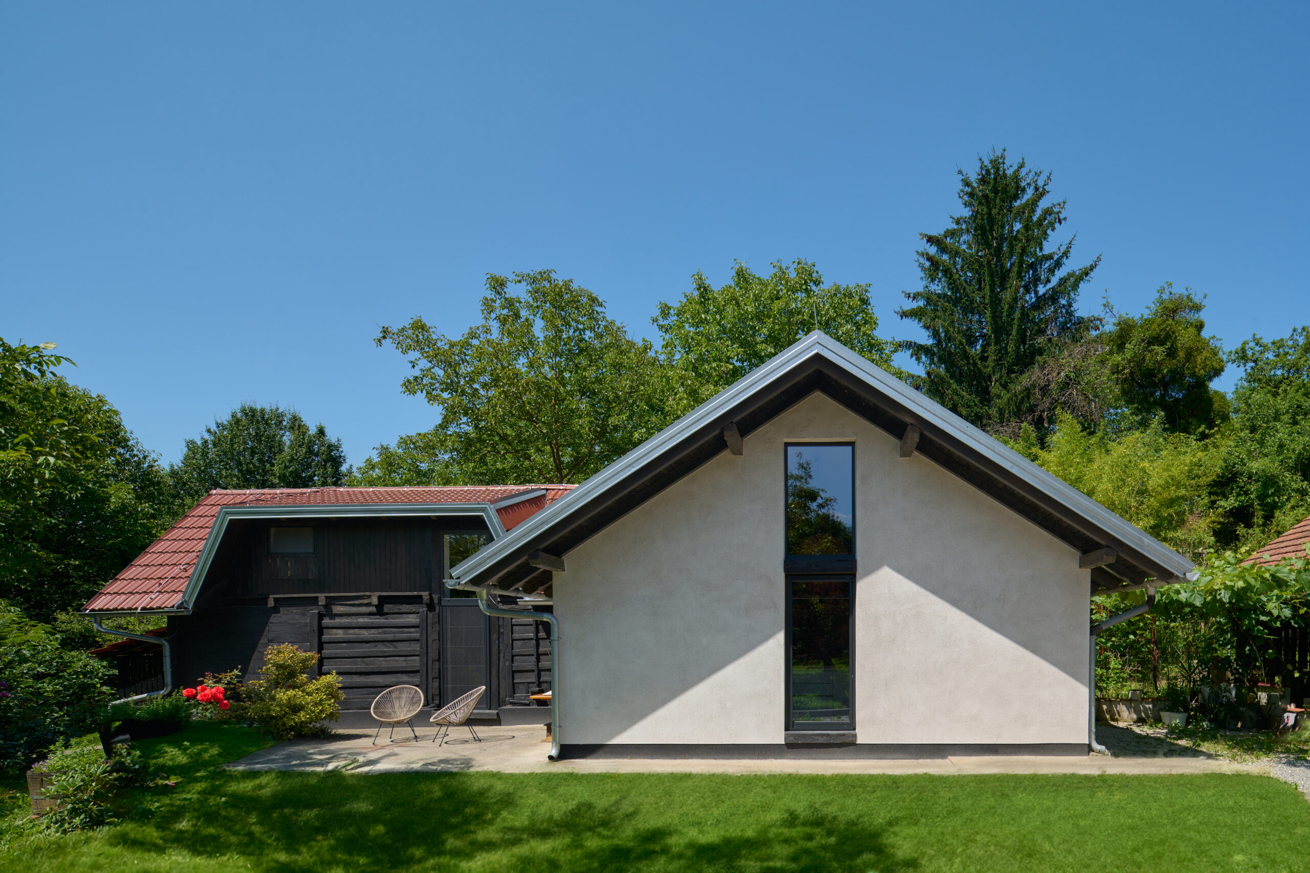 A white house with a large window surrounded by many trees.